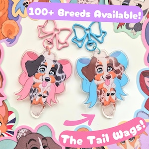 May include: Two acrylic keychains featuring illustrated Australian Shepherd puppies with large eyes and tongues out. One has a pink bow and clasp, the other a blue bow and clasp. Text reads 100+ Breeds Available! and The Tail Wags!