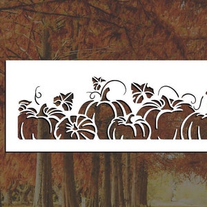 May include: A white silhouette of a row of pumpkins with leaves and vines. The pumpkins are various sizes and shapes. The silhouette is against a background of fall foliage.