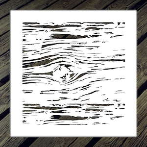 May include: A white stencil featuring a detailed wood grain pattern with a prominent knot. The design is cut out, revealing the wood grain texture. The stencil is placed on a wooden surface, creating a contrast between the white design and the natural wood.