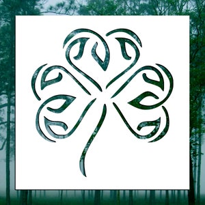 May include: A black and white stencil of a stylized four-leaf clover with intricate details.