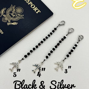 May include: Three black and silver beaded chains with airplane charms. The chains are 3, 4, and 5 inches long. The text "Black & Silver" is written below the chains.