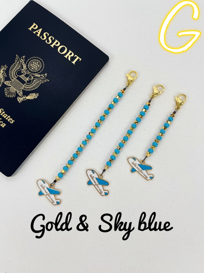 May include: Three gold and sky blue beaded chains with airplane charms. Each charm has the text "take me for a way" on it. The chains are hanging from a white surface. The words "Gold & Sky blue" are written below the chains.