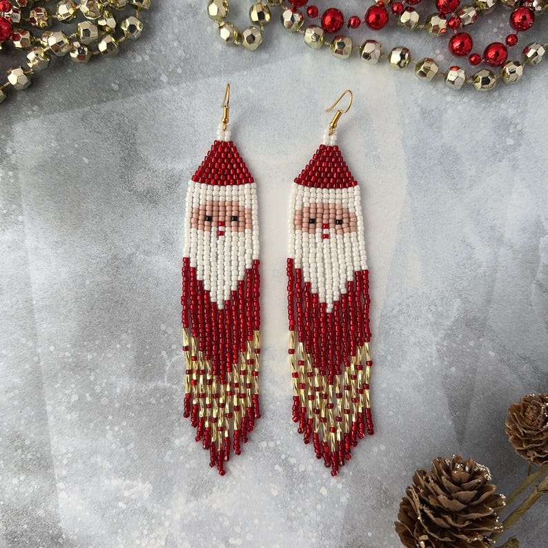 May include: Red and white beaded earrings with a Santa Claus design. The earrings are long and dangle, with gold beads at the bottom.