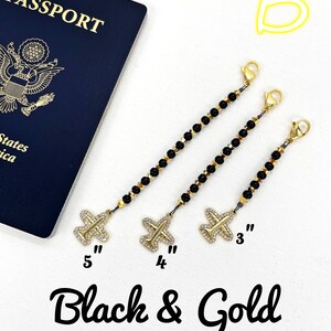 May include: Three black and gold beaded chains with airplane charms. The chains are 3 inches, 4 inches, and 5 inches long.  The charms are gold with rhinestones.  "Black & Gold" is written below the chains.
