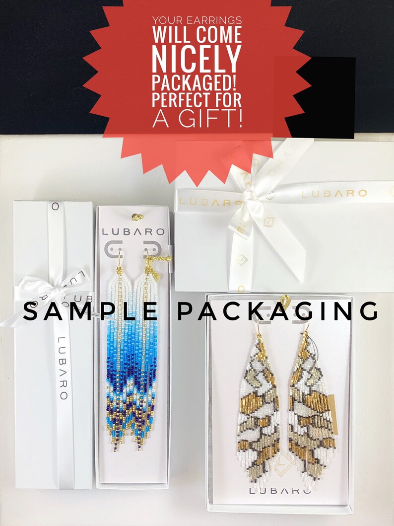 Puede incluir: Dos pares de pendientes de cuentas en cajas blancas con el nombre de la marca "LUBARO" impreso en ellas. Los pendientes est&aacute;n empaquetados en cajas blancas con una cinta blanca. El texto "YOUR EARRINGS WILL COME NICELY PACKAGED! PERFECT FOR A GIFT!" est&aacute; impreso en rojo sobre un fondo blanco.