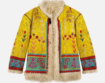 May include: A yellow embroidered coat with a cream-colored shearling collar and lining. The coat features colorful floral and paisley embroidery in red, blue, and pink. The coat has a button closure.