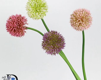 May include: Four artificial allium flower stems with spherical blooms in shades of light green, dusty pink, deep purple, and soft peach. Each flower head is composed of numerous small, star-shaped florets attached to slender, smooth green stalks.
