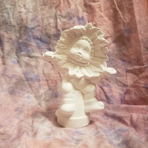 Könnte beinhalten: Weiße Keramikfigur eines lächelnden Kindes mit einem Sonnenblumenkopf, das auf einem Sockel sitzt. Die Figur ist zum Bemalen bereit.