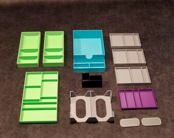 May include: An assortment of colorful desk organizers in various shapes and sizes. Includes green, blue, gray, black, and purple trays and containers. The organizers are designed to hold office supplies and keep a desk tidy.