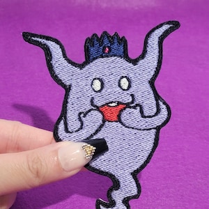 May include: Purple embroidered iron-on patch of a cartoon ghost wearing a crown. The ghost has a red mouth and white eyes.