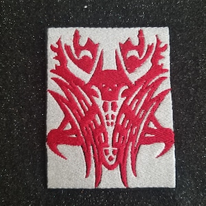 Op de afbeelding: Rode geborduurde patch met een gestileerd krabontwerp op een witte achtergrond.