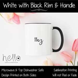 May include: White ceramic mug with a black rim and handle. The mug has a black design that says "hello" with a heart and "GRASSHOPPER" underneath. The mug also has the text "11oz" printed on it.