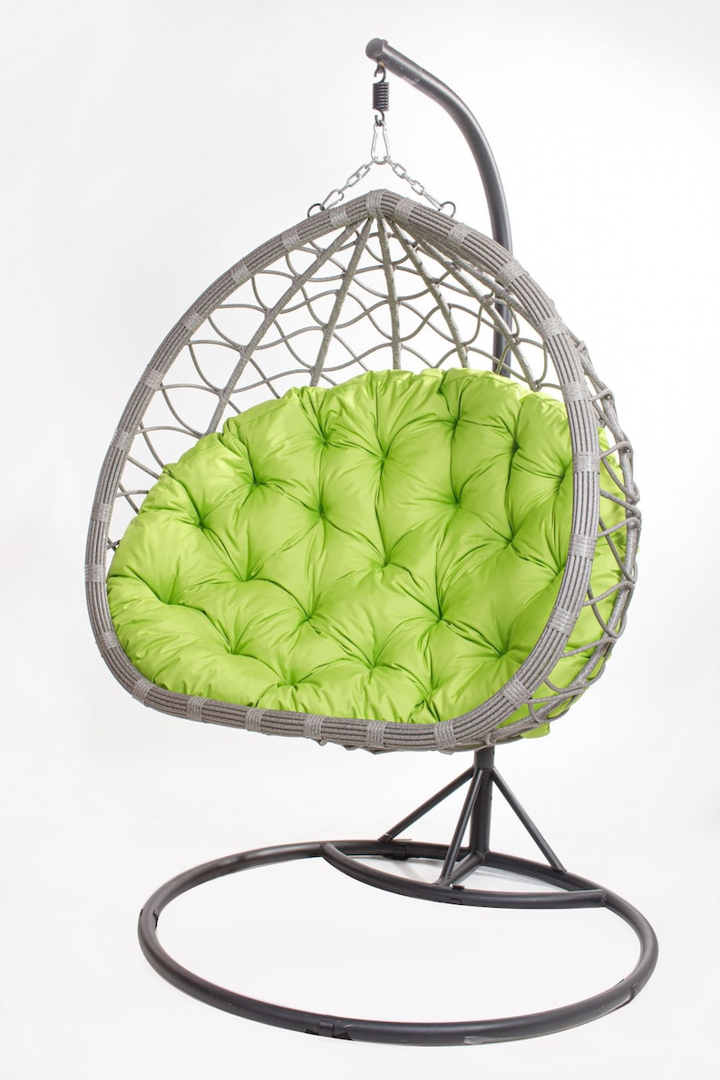 May include: A gray wicker egg chair with a bright green tufted cushion. The chair hangs from a metal frame with a circular base. The chair is designed for outdoor or indoor use.