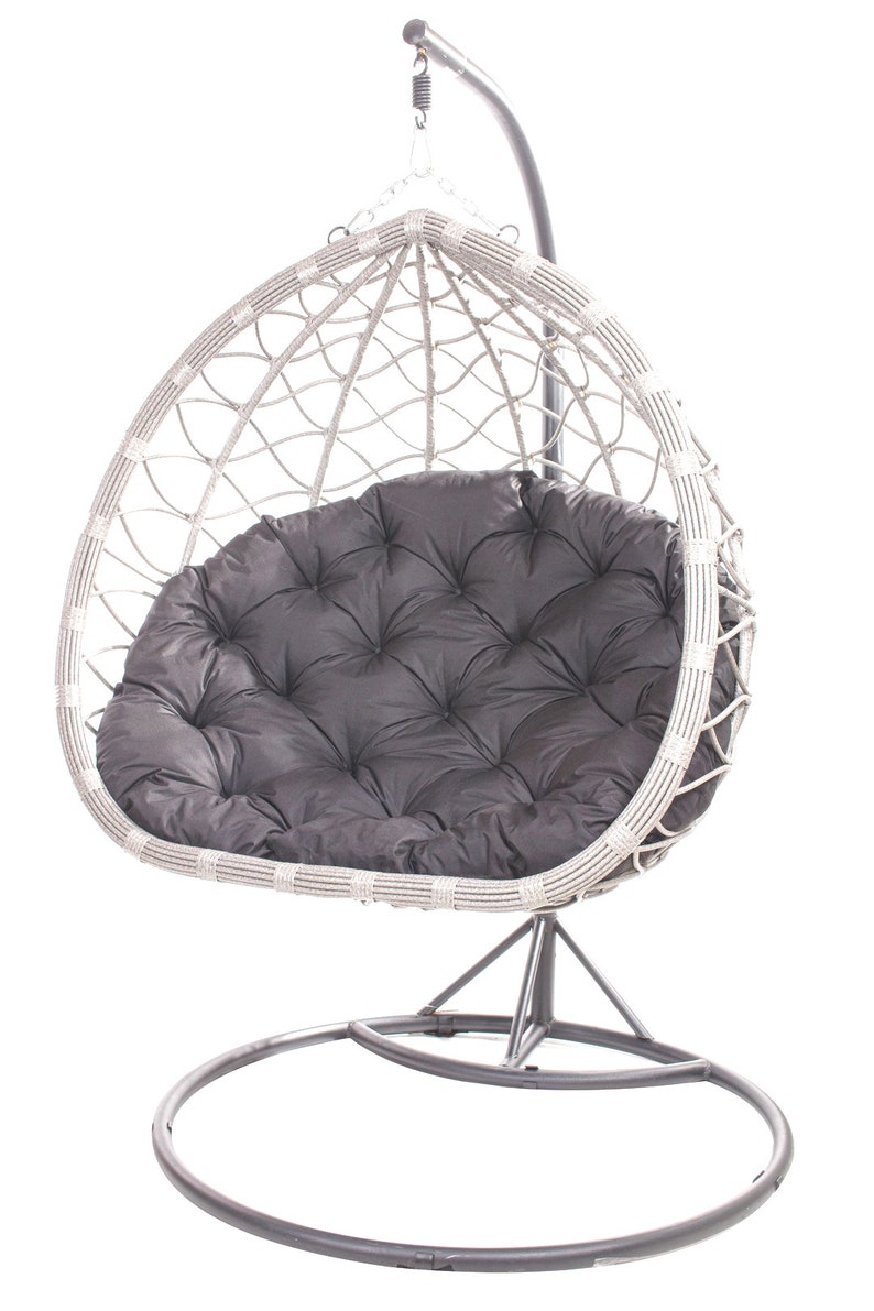 May include: A gray hanging egg chair with a dark gray cushion. The chair is made of woven material and hangs from a metal stand. The cushion has a tufted design. The chair is designed for outdoor or indoor use.