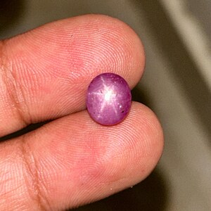 May include: A pink star ruby gemstone with a six-pointed star in the centre.