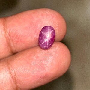 Op de afbeelding: Een roze ovale edelsteen met een stervormig patroon erin. De edelsteen is gezet in een zilveren ring.