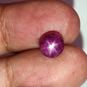 Op de afbeelding: Een diep roze ster-robijn edelsteen met een zespuntige ster in het midden.