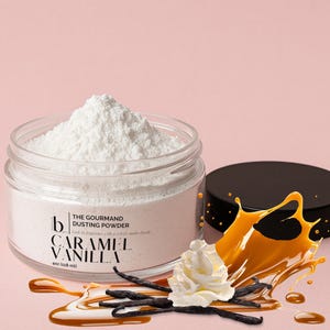 May include: A clear glass jar filled with white dusting powder, labeled "THE GOURMAND DUSTING POWDER CARAMEL VANILLA 4oz (118 ml)". The image includes a swirl of caramel, vanilla beans, and whipped cream against a pink background.