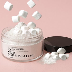 May include: A glass jar filled with white dusting powder and marshmallows, with some marshmallows floating above. The jar has a black lid and the text "MMM... MARSHMALLOW" on the label. The jar contains 118 ml of product.