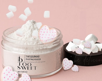 May include: A clear glass jar filled with white dusting powder, topped with marshmallows and heart-shaped cookies with pink polka dots. The jar has a black lid and the text "TOO SWEET". The jar contains 4oz (118 ml) of product.