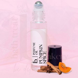 May include: A clear glass roller bottle with a black label that reads "Bath Treat" "Perfume Oil" "Pumpkin Spice". The bottle is sitting on a pink surface with cinnamon sticks, star anise, and a slice of pumpkin.