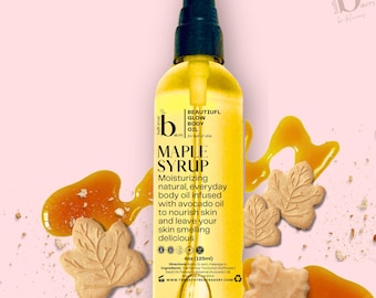 May include: A 4 ounce (125 ml) bottle of maple syrup scented body oil. The bottle is clear and yellow with a black pump top. The label is white with black text and a maple leaf design. The text on the label reads "Beautiful Glow Body Oil" and "Maple Syrup".
