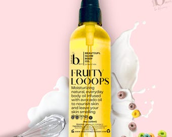 May include: A yellow bottle of body oil with a black pump top and label that reads "Bath Treat Bakery" and "Fruity Loops". The label also says "Moisturizing natural, everyday body oil infused with avocado oil to nourish skin and leave your skin smelling delicious". The bottle is sitting on a white surface with a pink background.