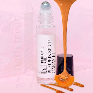 May include: A clear glass bottle with a rollerball top filled with a light brown liquid. The bottle has a white label with black text that reads "PERFUME OIL PUMPKIN SPICE CARAMEL" and a small black logo that reads "bath treat". The bottle is surrounded by a light brown liquid that is dripping from the top of the image.
