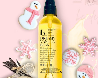 May include: A 4 ounce bottle of Dreamy Vanilla Bean body oil from Bath Treat Bakery. The bottle is yellow and has a black label with white text. The text on the label reads "Beautiful Glow Body Oil" and "Dreamy Vanilla Bean". The bottle is surrounded by pink and white snowflake and snowman-shaped cookies.