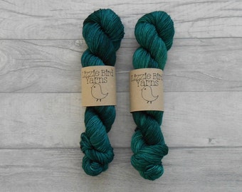 Könnte beinhalten: Zwei Knäuel tealgrünes Garn mit einem braunen Etikett, auf dem "Lizzie Bird Yarns" steht und eine kleine Vogelillustration.