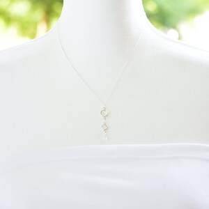 May include: A silver necklace with a delicate chain and three small, round, open circle pendants.