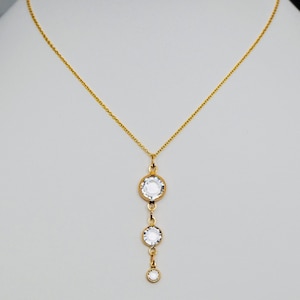 May include: A gold chain necklace with a pendant featuring three clear round crystals.