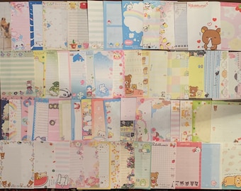 May include: A collection of 40 colourful stationery sheets featuring various cute cartoon characters, including bears, penguins, and bunnies. The sheets have different patterns and designs, including stripes, polka dots, and floral prints. Some sheets have lined paper, while others have blank space for writing or drawing.