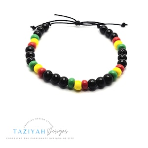May include: A black beaded bracelet with red, yellow, and green beads. The bracelet is tied with a black cord.