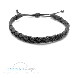 May include: A black braided leather bracelet with adjustable closure. The bracelet is made of a thick, durable leather cord and is designed to be comfortable to wear.