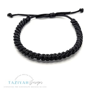 May include: A black braided cord bracelet with adjustable closure. The bracelet is made of a thick, durable cord and is perfect for everyday wear.