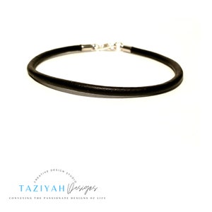 May include: A black leather bracelet with a silver clasp.