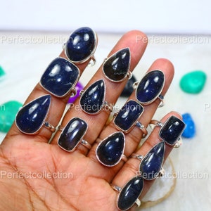 Puede incluir: Una colección de 12 anillos de plata con engastes de piedras preciosas azules. Los anillos presentan una variedad de formas, incluyendo redondas, ovaladas y cuadradas. Las piedras preciosas son de un color azul intenso y tienen un acabado brillante.