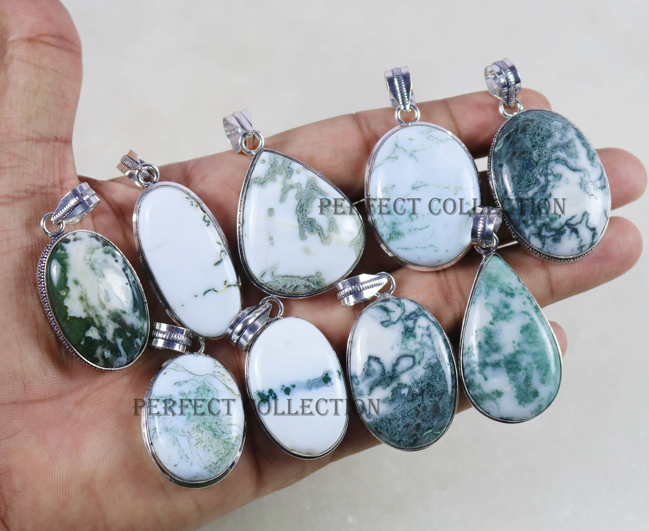 May include: A collection of gemstone pendants with silver-colored metal findings. The pendants feature white and green moss agate stones in various shapes, including oval and teardrop. The text "PERFECT COLLECTION" is visible on some pendants.
