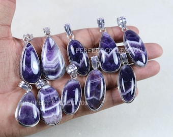 May include: A collection of 10 amethyst gemstone pendants with silver settings. The pendants are in various shapes, including teardrop and oval. The amethyst is a deep purple color with white striations.