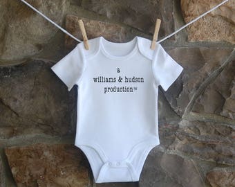 Puede incluir: Un body blanco para bebé con texto negro que dice "a williams & hudson production™".