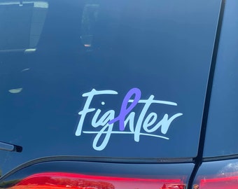Puede incluir: Una calcomanía de vinilo blanco con la palabra "Fighter" en una fuente cursiva. Una cinta morada está incorporada en la palabra "Fighter".