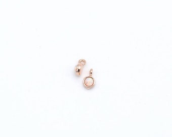 May include: Two rose gold charms, one with a round opal stone and the other with a simple loop.