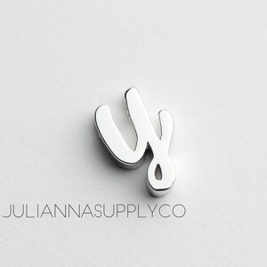 May include: Silver charm in the shape of the letter "y" in a cursive style.