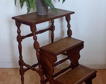 Una preciosa escalera de biblioteca, elegante y práctica, hecha de madera torneada y cuero.