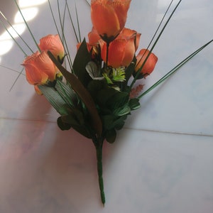 Peut inclure: Un bouquet de roses en soie orange avec des feuilles et des tiges vertes.