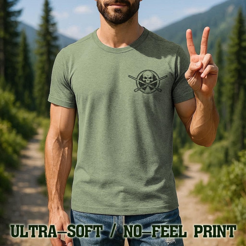 A man wearing a green t-shirt with a skull and crossbones design is making a peace sign with his hands.