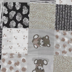 May include: A patchwork fabric with various patterns in shades of gray and brown. The patterns include stripes, clouds, hearts, and dots. There are also two embroidered bears on the fabric.
