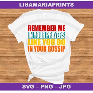 May include: White t-shirt with the text "Remember me in your prayers like you do in your gossip" in red, yellow, and green.