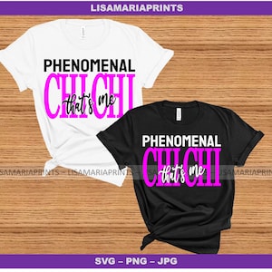 以下が含まれることがあります： 黒とピンクの文字で「Phenomenal Chichi that's me」と書かれたTシャツ2枚。Tシャツは木製の背景の上に置かれています。